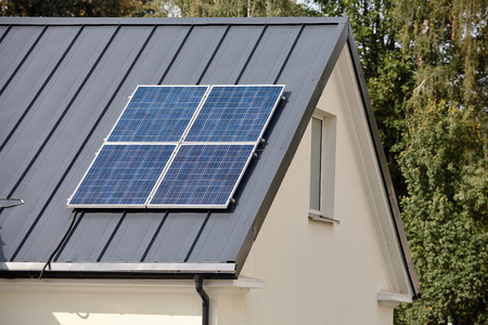 Solar panels installed and in use for renewable ecological clean green energy on dark metal roof of rural home.の写真素材