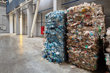 Compressed bales of polyethylene used PET bottles from drinks sorted and packaged for further processing workshop of a modern waste recycling plant with copy space. Concept of renewability of raw materials and protection of environment from pollution.の写真素材