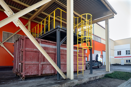 At modern waste recycling plant, process of loading sorted garbage from conveyor belt into container for further transportation by truck recycling or disposal.の写真素材