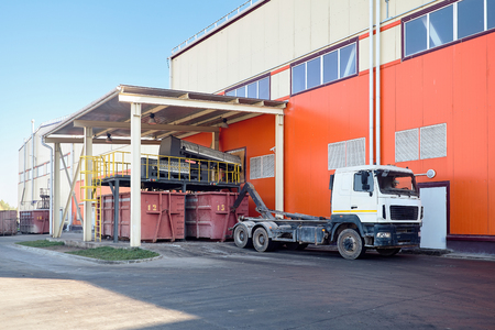 At modern waste recycling plant yard, process of loading sorted garbage from conveyor belt into container for further transportation by truck recycling or disposal.の写真素材