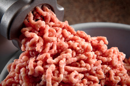 Minced meat coming out from modern electric grinder close-up. Healthy fresh homemade minced meat. Place for copyspace.の写真素材