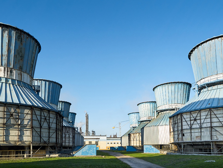 Row of old fan cooling towers for cooling circulating water of chemical plant under clear blue sky.の写真素材