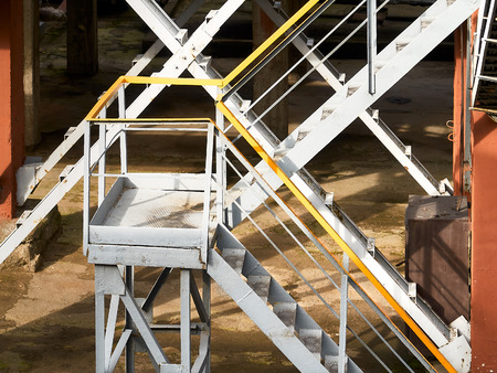 Industrial building structure fragment featuring metal staircases and pillars. Abstract image on the subject of modern architecture, industry and technology.の写真素材