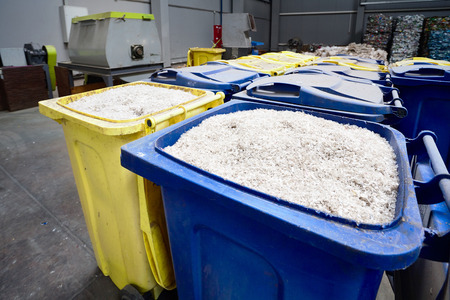 Modern plant for processing and sorting garbage. Containers with shredded plastic prepared for further processing remelting and recycling with shredder and bales of plastic waste in the background.の写真素材