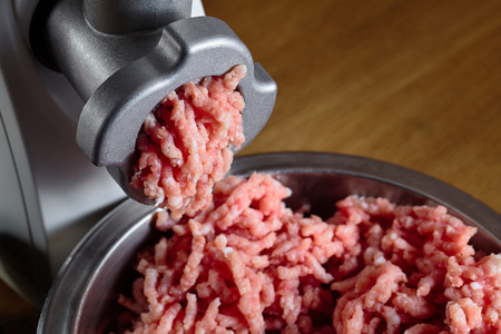 Minced meat coming out from modern electric grinder on oak table as baclground. Healthy fresh homemade minced meat. Place for copyspace.の写真素材