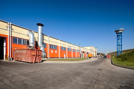Modern plant for recycling and mechanical waste sorting with fire water tower under clean blue sky.の写真素材