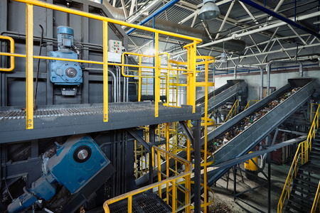 Refiner and chain-stepped conveyor equipment of modern waste recycling plant transports waste from receiving department to sorting, recycling and disposal.の写真素材