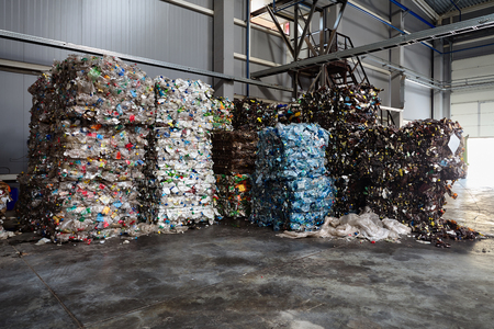 Pressed bales of polyethylene used bottles and PET juice packages sorted and packed for further processing at modern waste recycling plant with copy space. Concept of renewability of raw materials.の写真素材