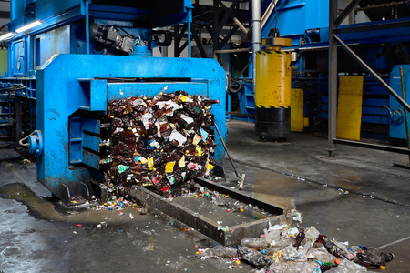 Modern waste sorting and recycling plant, hydraulic press makes wired bale from pressed PET bottles for processing and reuse of plastic. Concept of defence of environment by materials recycle.の写真素材