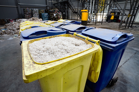 Modern waste processing and sorting plant. Containers with shredded plastic prepared for further processing remelting and recycling with shredder and bales of plastic waste in the background.の写真素材