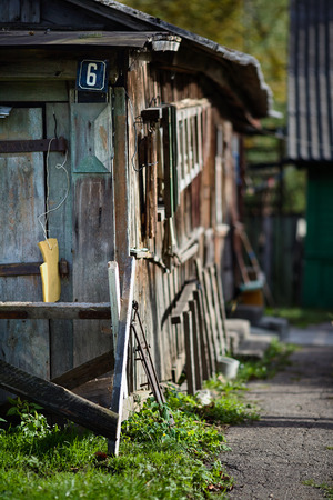 Blue painted metal house nameplate or street sign with six digit on wooden wall of barn near out of focus rural house background.の写真素材