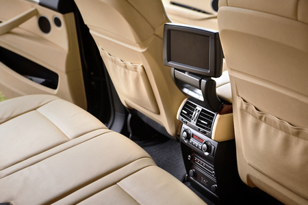Car inside. Interior in cream colors leather of prestige luxury modern car. Swivel display for back seats passenger with media control panel copy space mock up.の写真素材
