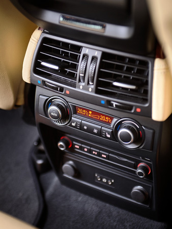 Modern car climate control panel for passengers in rear row with shallow depth of field. Four zone climate control. Car interior detail. Back passenger air vents and audio system headphoneの写真素材