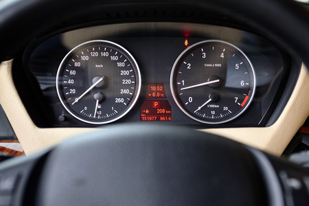 Multifunctional panel of luxury car with speedometer tachometer indicators and part of steering wheel out of focus closeup.の写真素材