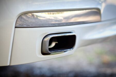 Low angle view of the exhaust pipe of a car with selective focus on tailpipe. Concept of greenhouse effect and air pollution due to carbon monoxide and dioxide emissions from fuel combustion.の写真素材