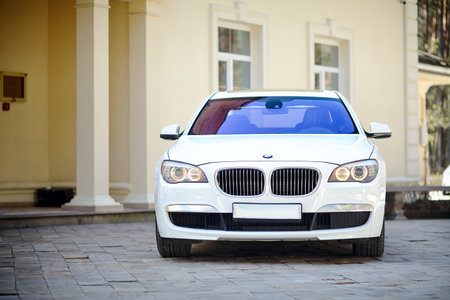 Grodno, Belarus, May 16, 2013: Modern luxury BMW 750Li XDrive car front view parked on stone paved parking near ancient house horizontal.のeditorial素材