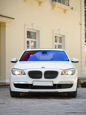 Grodno, Belarus, May 16, 2013: Modern luxury BMW 750Li XDrive car front view parked on stone paved parking near ancient house vertical.のeditorial素材
