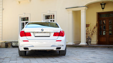 Grodno, Belarus, May 16, 2013: Modern luxury BMW 750Li XDrive car rear back view parked on stone paved parking near ancient house horizontal.のeditorial素材