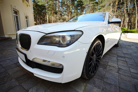 Grodno, Belarus, May 16, 2013: Modern luxury BMW 750Li XDrive car front three-quarter wide view parked on stone paved parking near ancient house.のeditorial素材