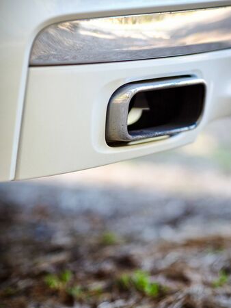 Low angle view of the exhaust pipe of a car with selective focus on tailpipe vertical. Concept of greenhouse effect and air pollution due to carbon monoxide and dioxide emissions from fuel combustion.の写真素材