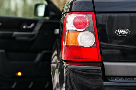 Grodno, Belarus, December 2012: Land Rover Range Rover Sport V8 Supercharged. Left rear headlight of black SUV shot close-up with opened door out of focus on background with copy space.のeditorial素材