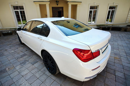 Grodno, Belarus, May 16, 2013: Modern luxury BMW 750Li XDrive car three-quarter upper wide view parked on stone paved parking near ancient house.のeditorial素材