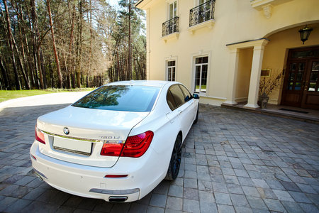 Grodno, Belarus, May 16, 2013: Modern luxury BMW 750Li XDrive car rear back upper view parked on stone paved parking near ancient house with balconies with wrought iron grilles.のeditorial素材