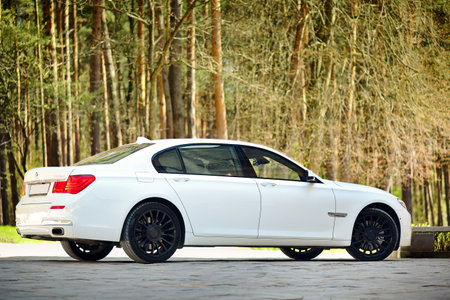 Grodno, Belarus, May 16, 2013: Modern luxury BMW 750Li XDrive car three-quarter side view parked on stone paved parking near ancient house.のeditorial素材
