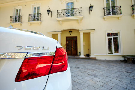 Grodno, Belarus, May 16, 2013: Modern luxury BMW 750Li XDrive car rear back close-up view with tail light parked on stone paved parking near ancient house with balconies with wrought iron grilles.のeditorial素材