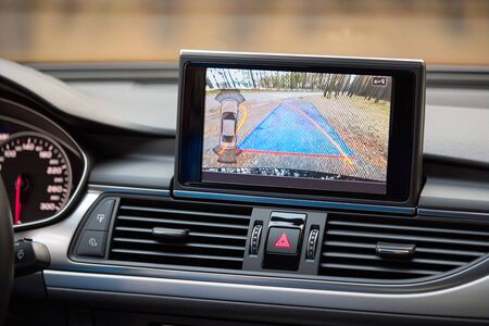 Interior of premium car with rearview camera dynamic trajectory turning lines and parking assistant steering wheel turned left. Driver assistance parking system. Help assist options of luxury car.の写真素材