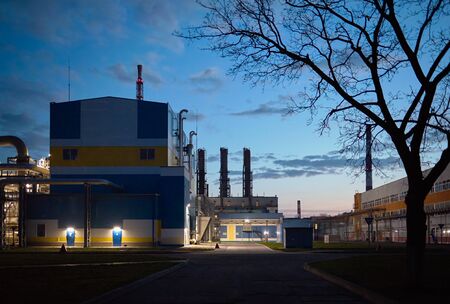 Beautiful scenic of petrochemical oil refinery plant shines with red and white lights at night with tree on foreground and copy space.の写真素材
