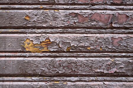 Old painted dilapidated flaky scaly wooden paint building wall brown chocolate colored yellow inside as design background or texture for backdrop.の写真素材