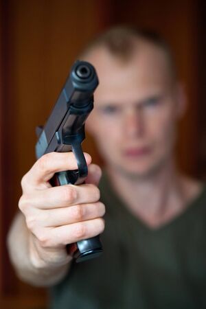 A man aims his semi automatic pistol. Selectively focused on the front of the gunの写真素材
