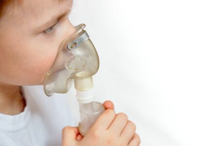 Child makes inhalation at home with nebulizer selective focuse on nebulaser mask with copy space. Example of combating respiratory diseases such as tracheitis bronchitis pneumonia.の写真素材