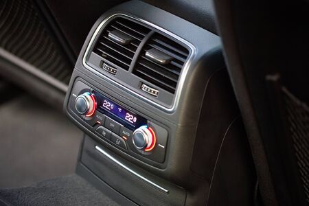 Control panel with digital multi color display and knobs for rear seat passenger in modern prestige luxury car interior selective focus with copy space.の写真素材