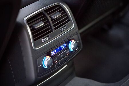 Control panel with digital multi color display and knobs for rear seat passenger in modern prestige luxury car interior selective focus with copy space.の写真素材