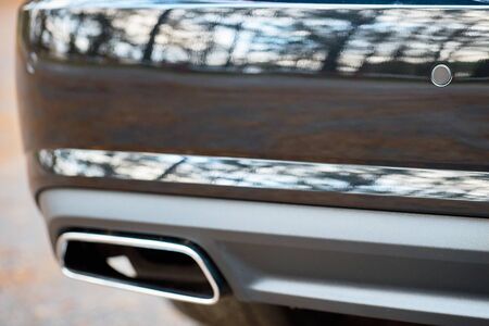 Selective focus on parking sensor exhaust pipe bumper at rear of black luxurious car bumper close up on light blurred backgroundの写真素材