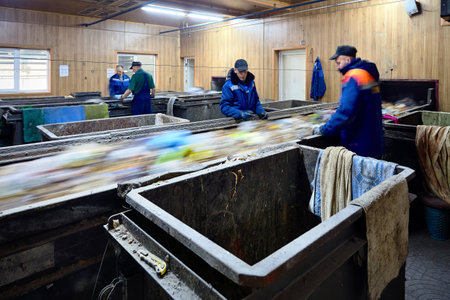GRODNO, BELARUS - OCTOBER 2018: Four workers in uniform working at waste processing plant sorting recyclable materials from garbage on conveyor belt with motion blur.のeditorial素材