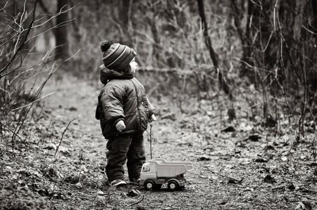 Little Boy With a Car Toy Got Lost In a Forest in black and whiteの写真素材