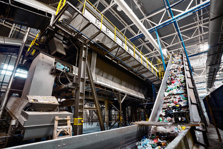 GRODNO, BELARUS - OCTOBER 2018: recycling plant conveyor belt transports garbage inside drum filter or rotating cylindrical sieve trommel or sorting pieces of garbage into various sizes fractions.のeditorial素材