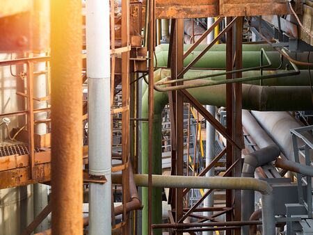 Tangle of pipes. Concept of complexity of petrochemical industry communications. Pipe weaving of various diameters with expansion joints and flanges with sunflare.の写真素材
