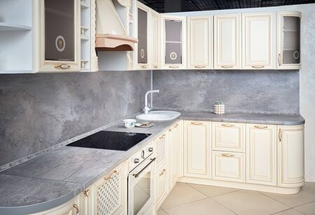 Interior of modern kitchen in classic style with golden elements in beige colors with built-in appliances electric or induction hob, electric oven stone sink and extractor fanの写真素材