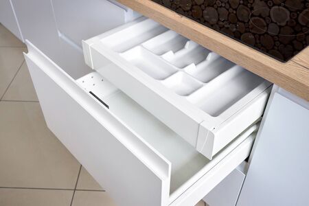 Solution for placing kitchen utensils in modern kitchen - horizontal sliding pullout drawer shelves storage in cupboard for kitchenware cookware under oak countertop with induction hobの写真素材