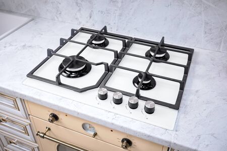Modern hob gas stove made of tempered white glass using natural gas or propane for cooking products on light countertop in kitchen interiorの写真素材