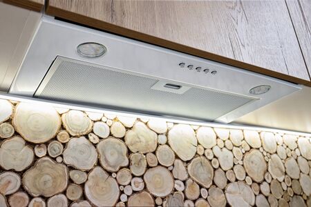 Cooker hood in the interior decorated with wall cross section of tree trunks of cutting tree, trunks placed together for interior decoration. Pile stacked natural sawn wooden logs stump cutの写真素材