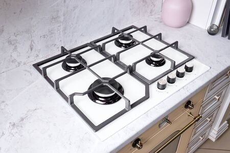 Modern hob gas stove made of tempered white glass using natural gas or propane for cooking products on light countertop in kitchen interiorの写真素材