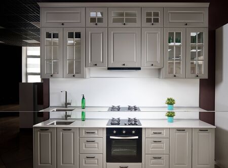 Interior of white and grey kitchen, horizontal, linear layout. Luxury modern fitted flat design kitchen with glass elementsの写真素材
