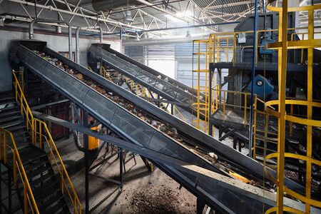 Conveyor with garbage at modern waste recycling plant transporting waste from receiving department to manual sorting department for further processing utilization and disposal of garbageの写真素材