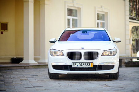 Grodno, Belarus, May 2013: Modern luxury BMW 750Li XDrive car front view parked on stone paved parking, near ancient house horizontal.のeditorial素材