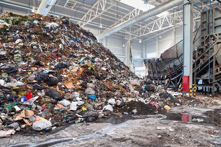 Solving problem of environmental pollution with waste at garbage processing plant - huge pile of garbage prepared for loading to conveyor belt for further sorting and processing, with copyspase.の写真素材
